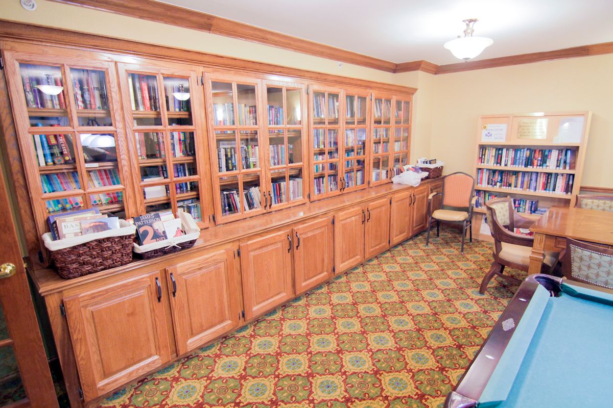 A cozy library room with wooden bookshelves filled with books and a patterned carpet floor.