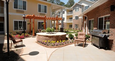 A beautifully landscaped courtyard with a pergola and outdoor seating in an apartment complex.