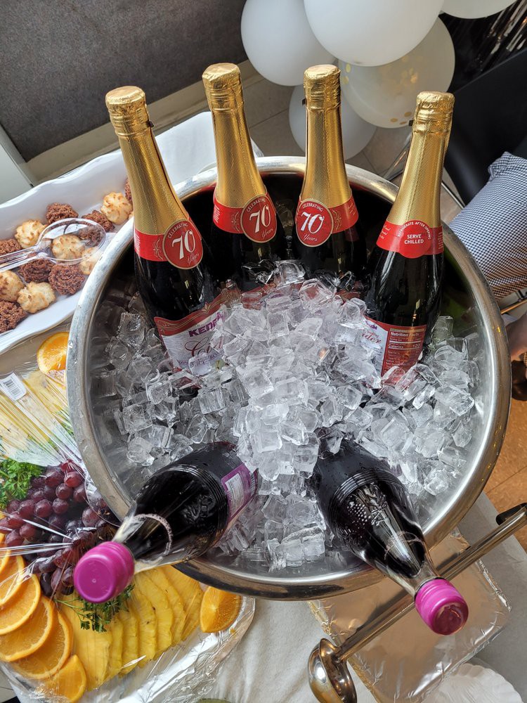 A festive display of chilled champagne bottles in an ice bucket, surrounded by grapes and light snacks.
