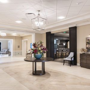 A modern lobby area with elegant decor and a central table displaying flowers.