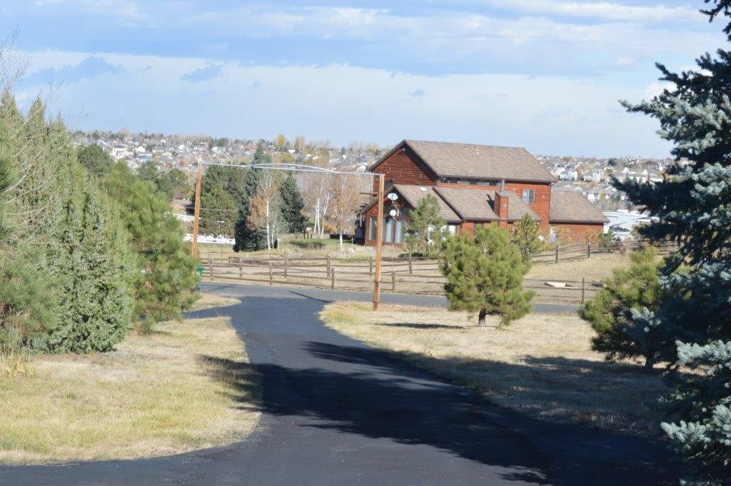 A peaceful countryside scene with a wooden house, surrounded by trees and a winding pathway.