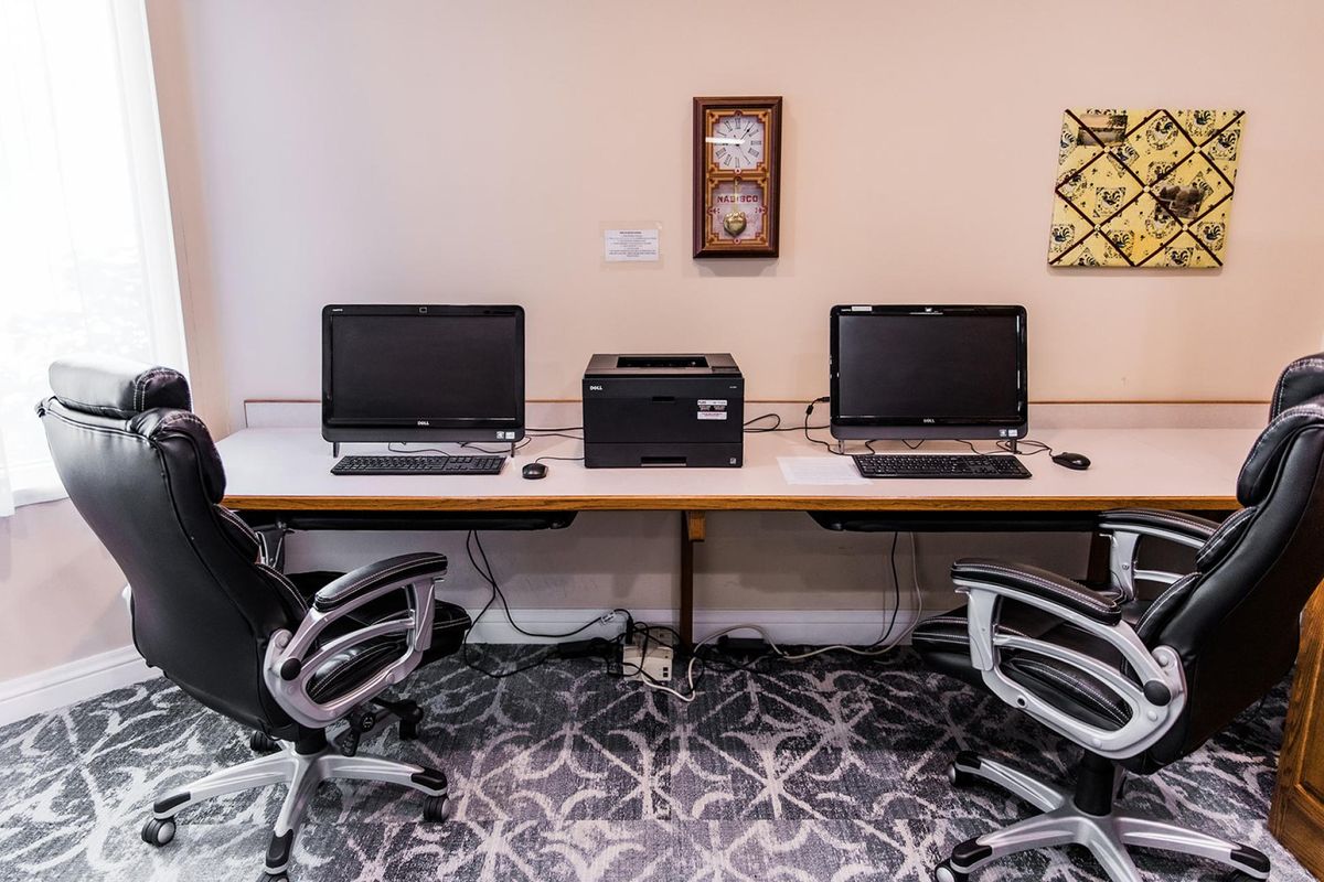 A modern workspace with computers and a printer on a shared desk.