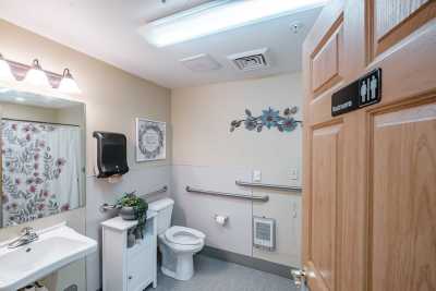 An accessible bathroom with a toilet, sink, and handrails.