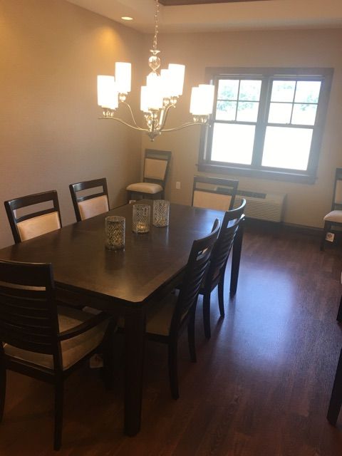 A dining room with a large table, several chairs, and a chandelier.