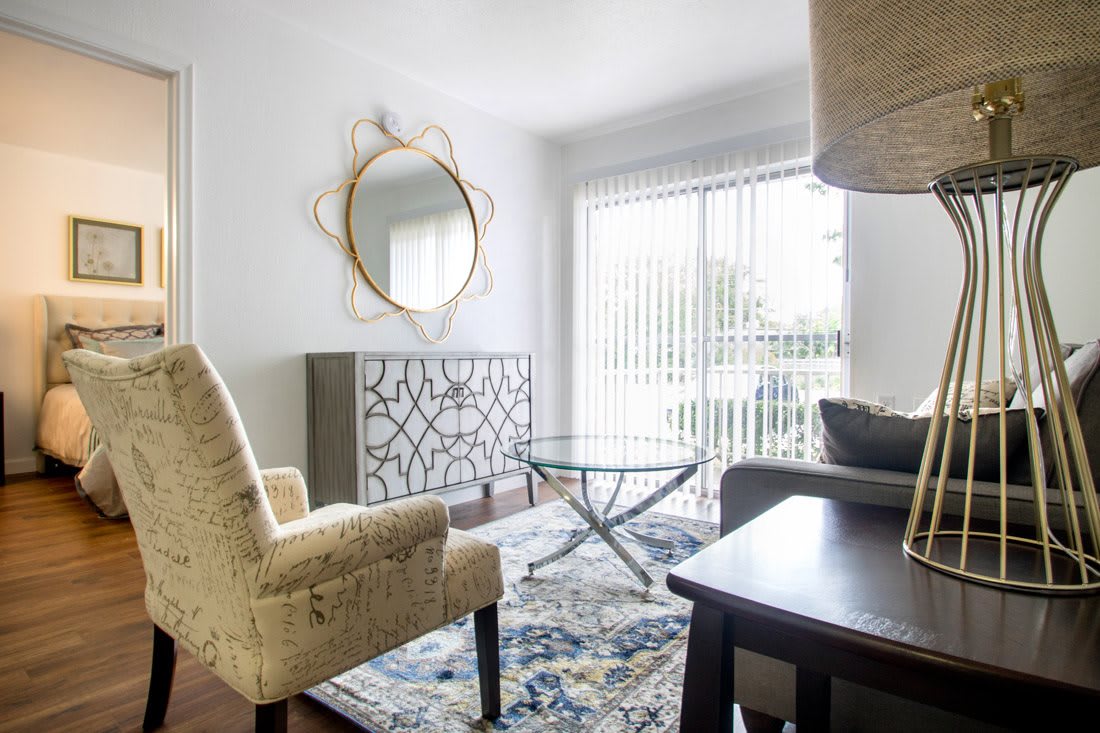A cozy living room with a patterned rug, modern furniture, and large windows allowing natural light.
