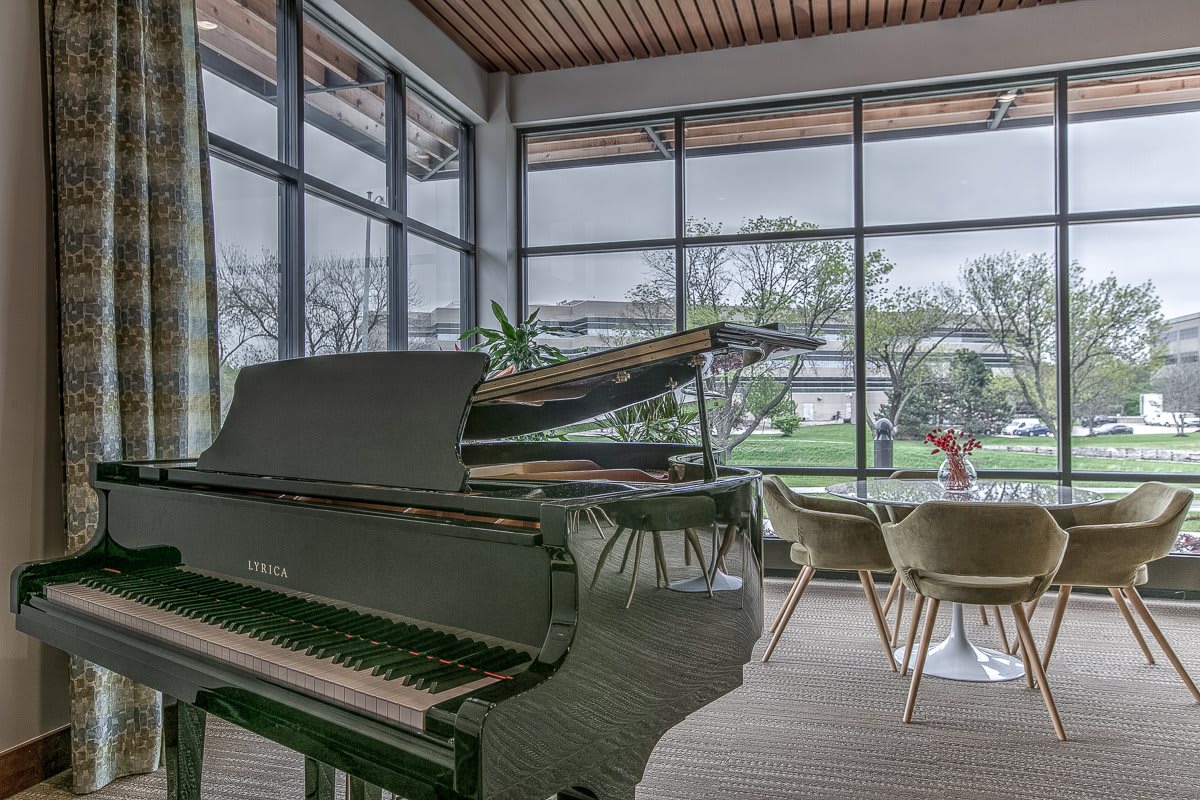A modern lounge with a grand piano and large windows providing natural light.