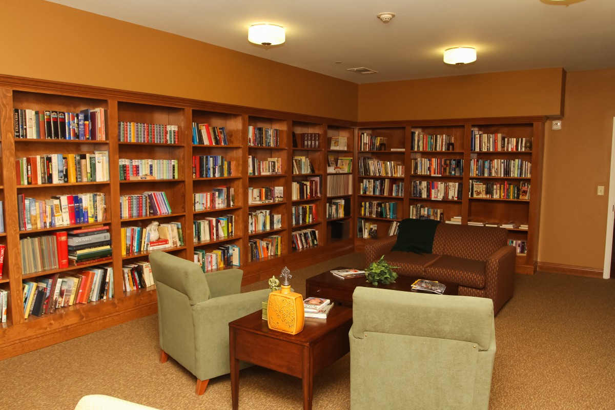 A cozy library reading area with bookshelves, chairs, and a couch.