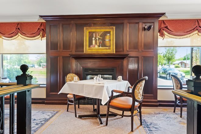 Cozy dining area with a wooden paneled fireplace and elegant decor.