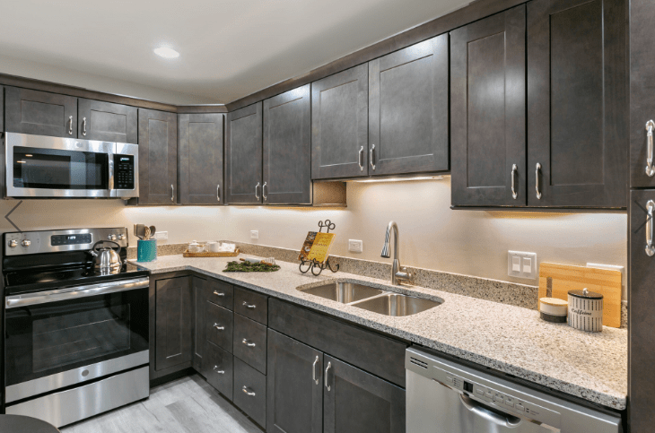 A modern kitchen with dark cabinets, stainless steel appliances, and granite countertops.