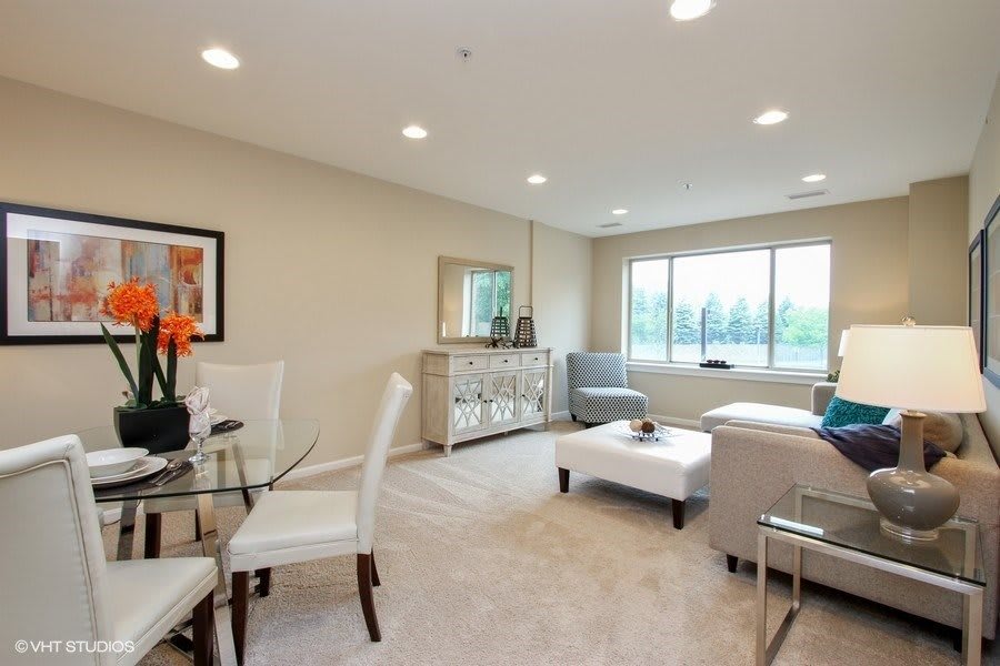 A modern living room with a seating area, dining table, and large window.