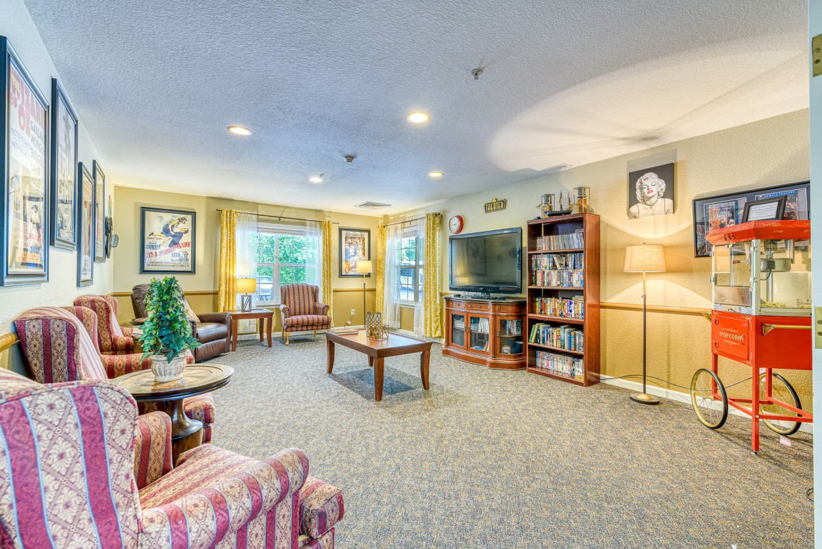 A cozy living room with comfortable seating, a television, and a bookshelf.