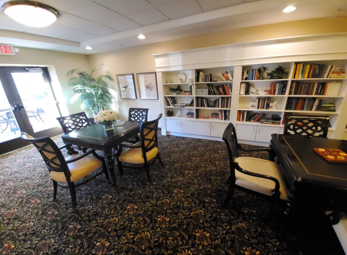 A cozy library space with bookshelves, tables, and chairs for reading.