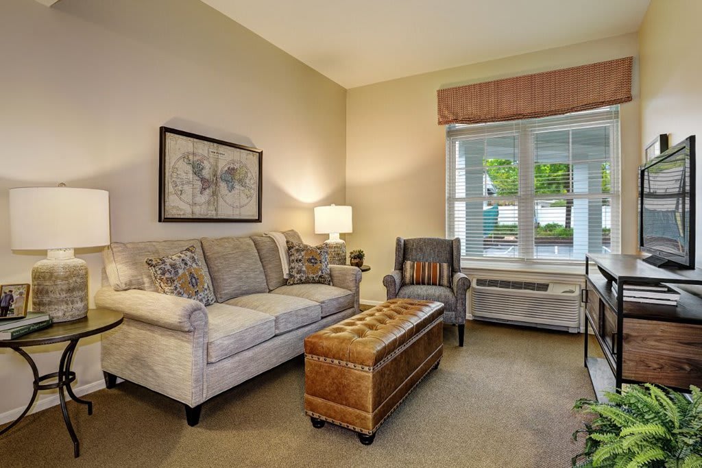 A cozy living room with a sofa, armchair, and a coffee table near a window.
