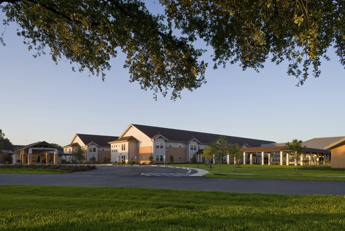 A scenic view of a large building surrounded by green grass and trees under a clear blue sky.