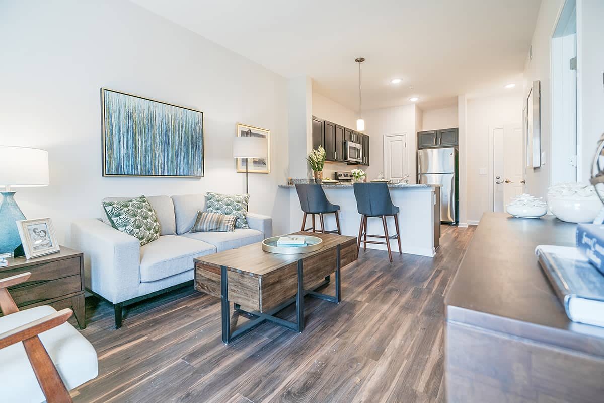 A modern open-layout living room and kitchen with stylish furniture and wood flooring.