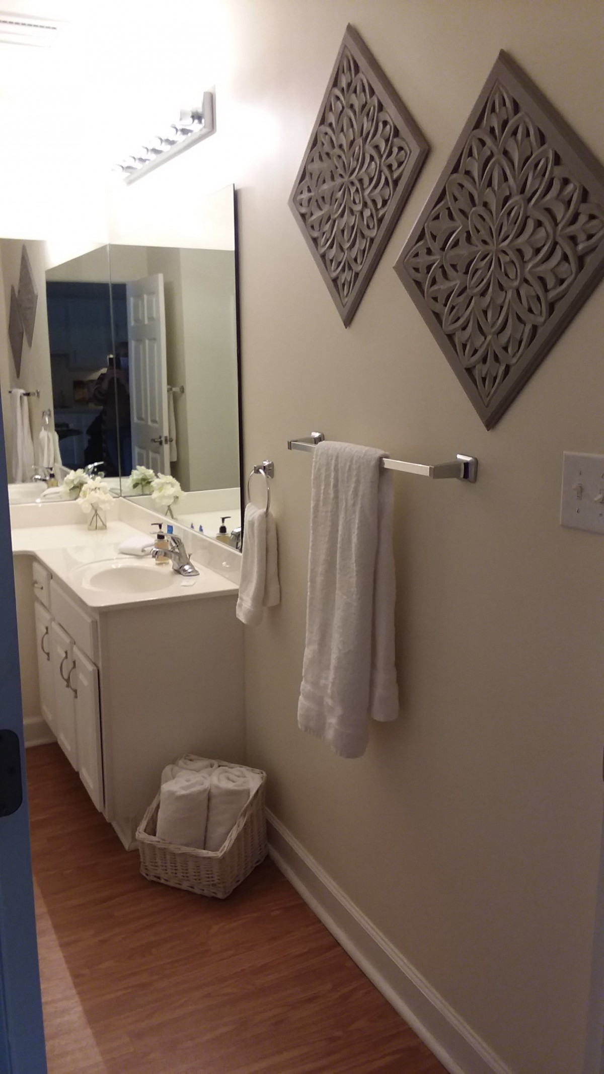 A neatly organized bathroom with a sink, mirror, and towels.