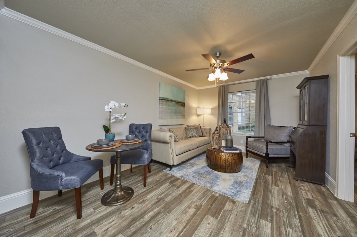A cozy living room with modern furniture and warm decor, featuring a beige sofa, blue chairs, a wood coffee table, and elegant lighting.