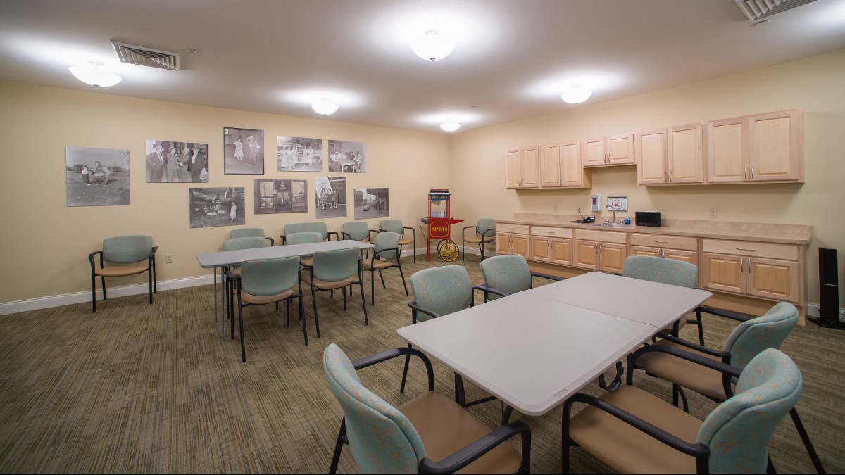 A communal dining area with tables, chairs, and a small kitchen setup.
