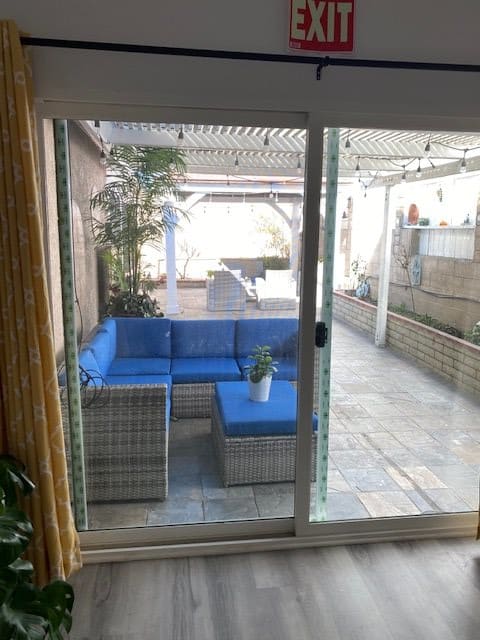 A cozy outdoor patio with blue cushioned seating and a glass sliding door.