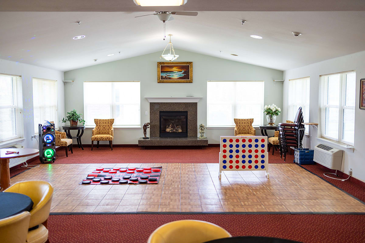 A spacious living room with a fireplace, large windows, and games like Connect Four set up on the floor.