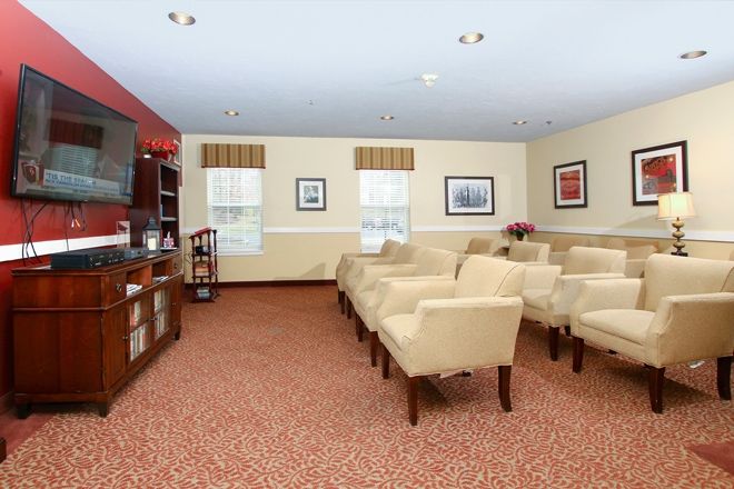 A well-arranged room featuring rows of beige chairs facing a television with framed art on the walls.