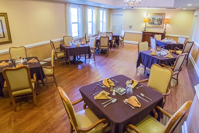 A neatly arranged dining room with multiple tables and chairs, set for a formal meal.