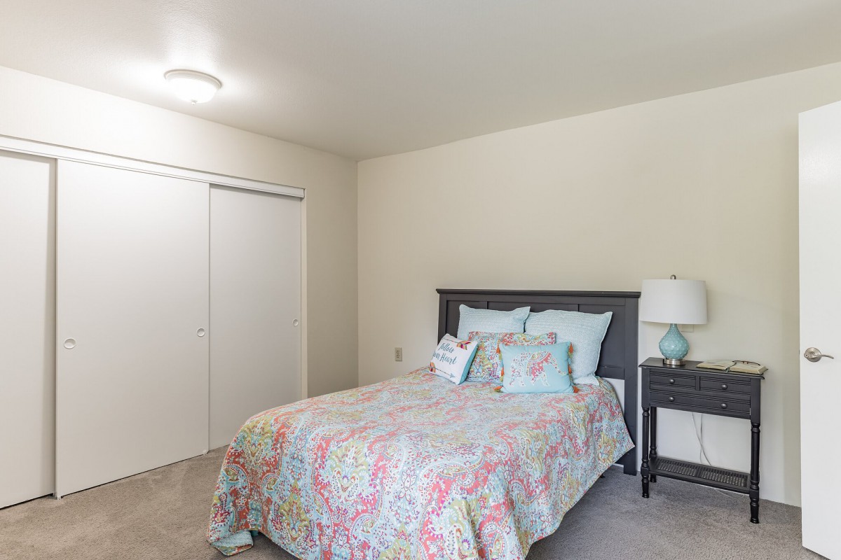 A cozy bedroom with a colorful bedspread and a nightstand lamp.