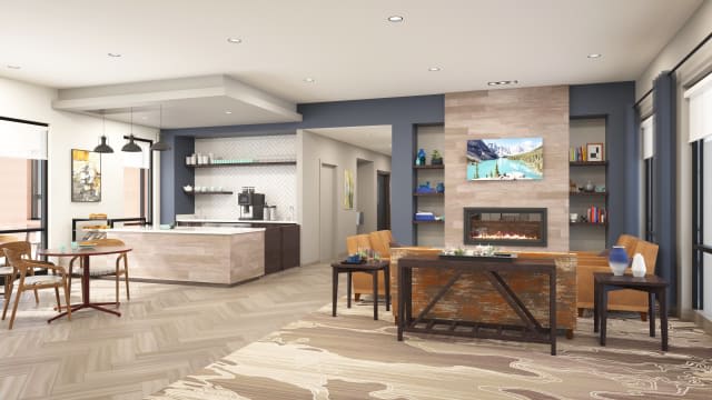 A modern open-plan living room with a kitchen area, featuring sleek furniture and a cozy fireplace.