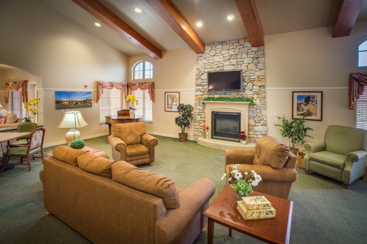 A cozy living room with a stone fireplace, comfortable seating, and a beamed ceiling.