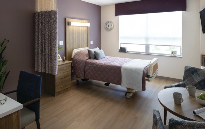 A modern hospital room with a single bed and minimalistic decor.