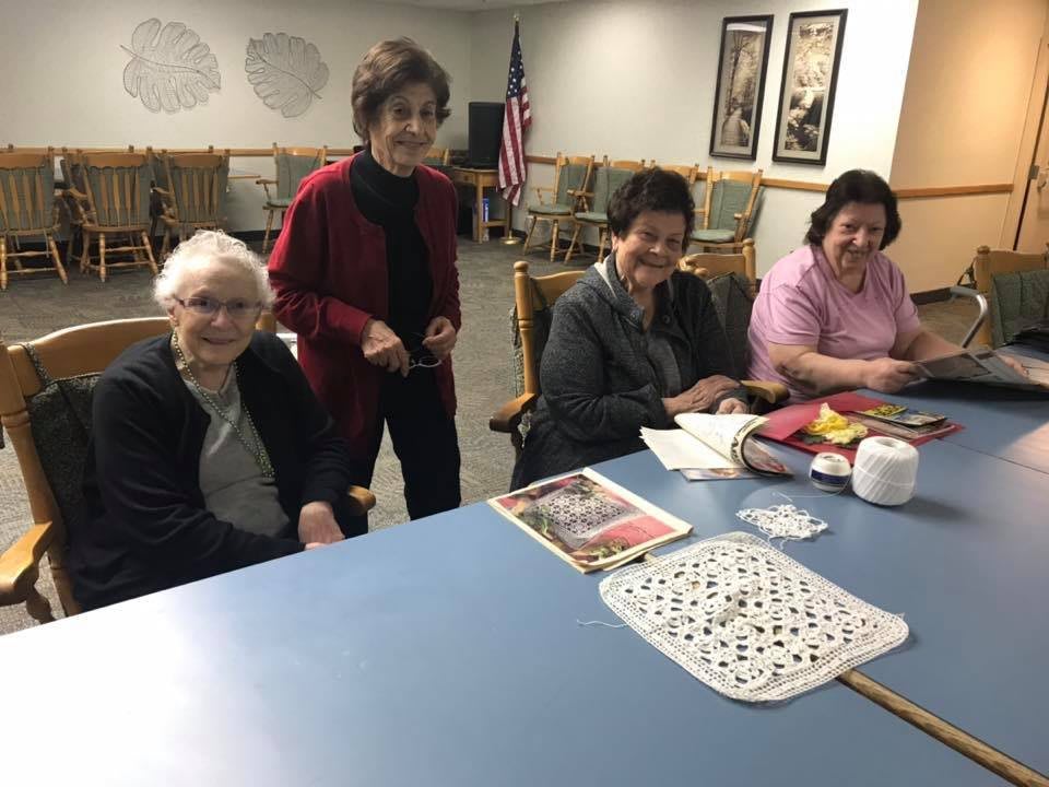 A group of elderly women gathered around a table, enjoying a recreational activity together.