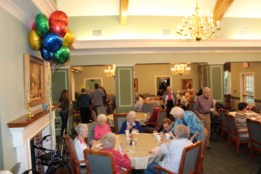 Seniors enjoying a lively gathering in a community dining room adorned with colorful balloons.
