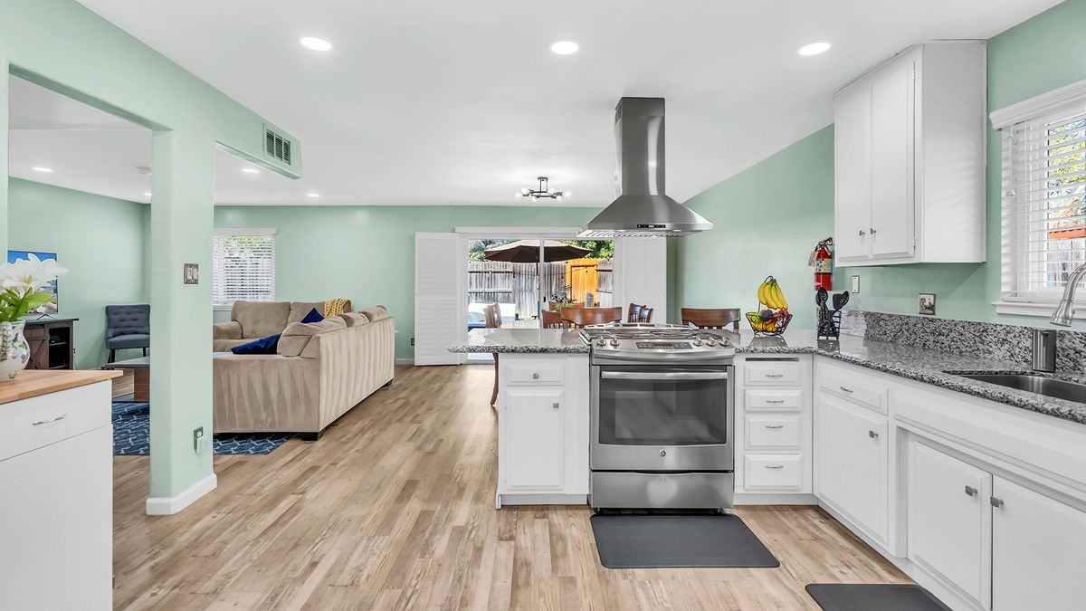 Modern open floor plan kitchen and living area with stainless steel appliances.