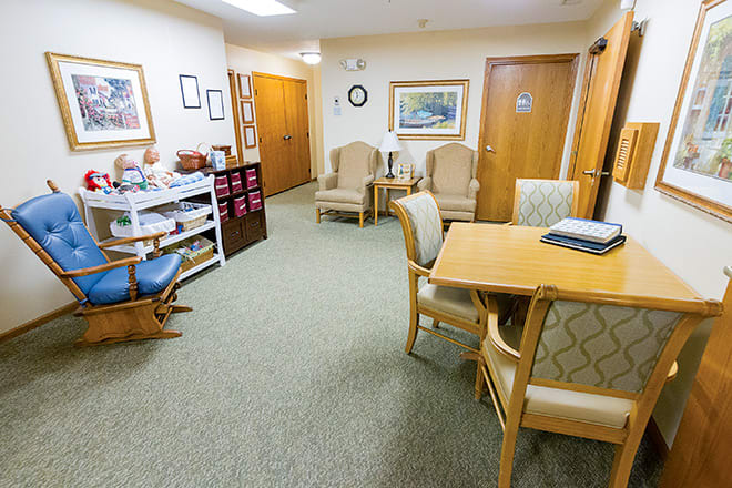 A well-furnished waiting room with chairs, a table, and artwork on the walls.