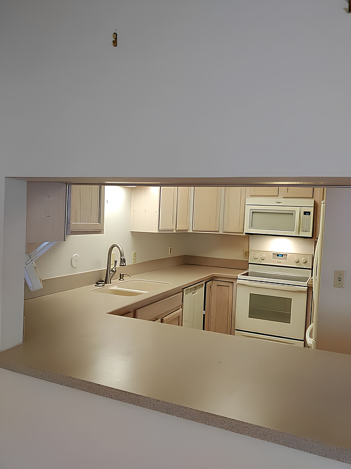 View of a kitchen with appliances and light-colored cabinetry.