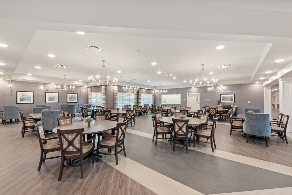 An elegantly designed dining area with wooden tables and chairs, illuminated by chandeliers.