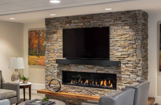 A modern living room with a stone wall fireplace and mounted TV, complemented by warm lighting.