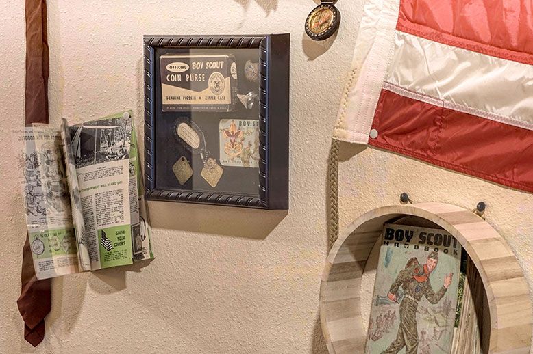A collection of vintage memorabilia including a framed display, newspaper clippings, and a scout-themed magazine on a wall.