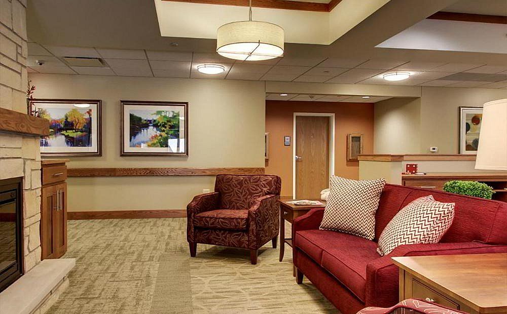 A modern lobby area featuring comfortable seating with a sofa and armchair, complemented by stylish lighting and artwork on the walls.