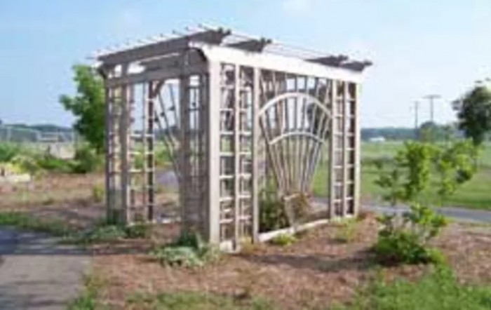 A wooden pergola with lattice design stands in a garden setting.