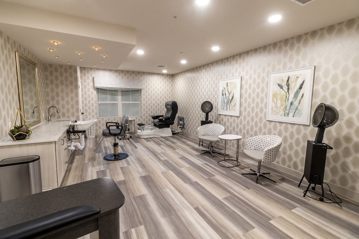 A modern salon interior featuring stylish chairs and artwork, with ample lighting and sleek decor.