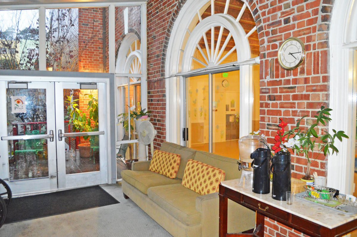 A cozy hotel lobby featuring brick walls, a comfortable couch, and decorative arched windows.