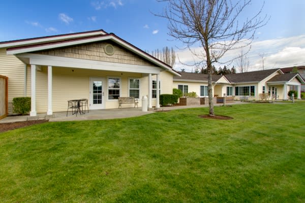 A suburban house with a well-maintained lawn and a small patio area.
