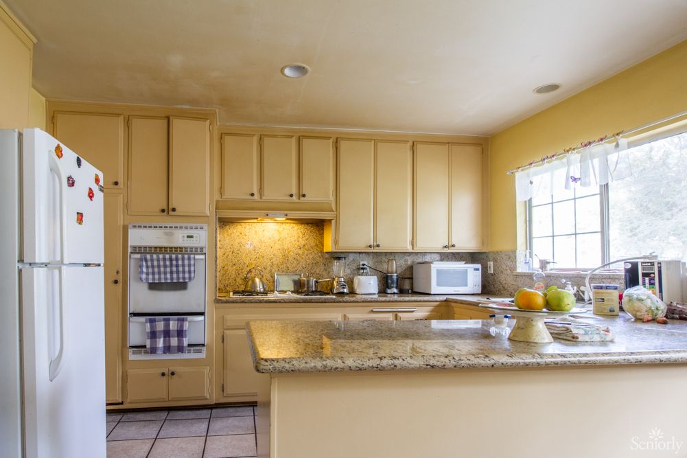 A spacious kitchen with wooden cabinets and a granite countertop.