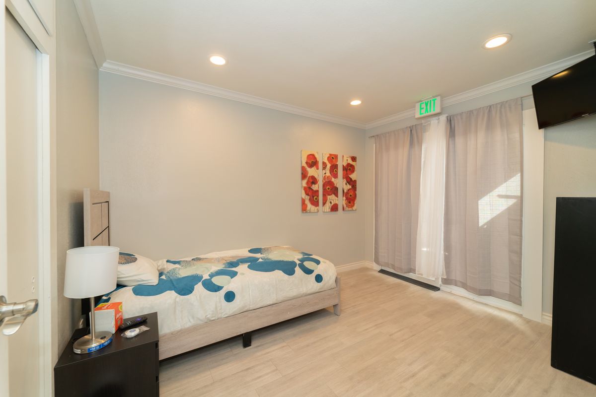 A minimalist bedroom with a bed, artwork on the wall, and soft lighting.