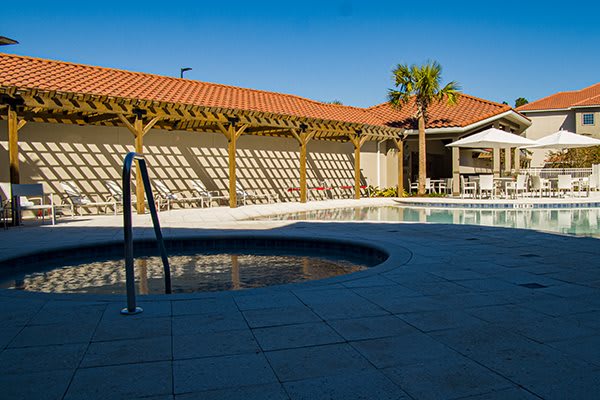 A serene outdoor pool area with a tiled patio and wooden pergola, perfect for relaxation and leisure.