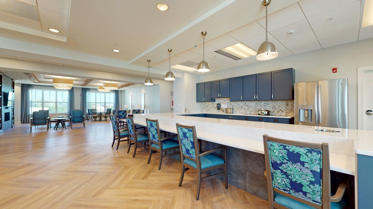 Modern kitchen interior with a large countertop, blue cabinets, and stylish pendant lighting.
