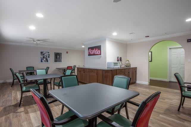 A communal dining area with multiple tables and chairs, featuring artwork on the walls.
