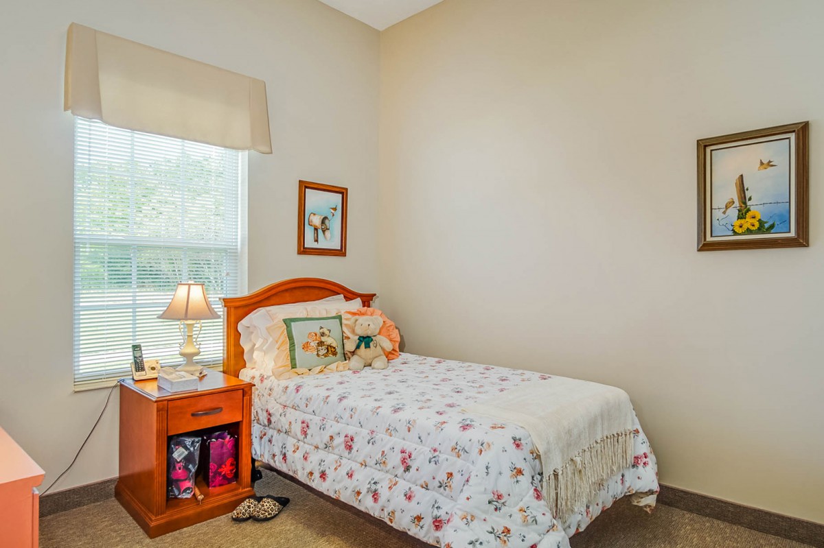A cozy bedroom with a single bed, nightstand, and window.