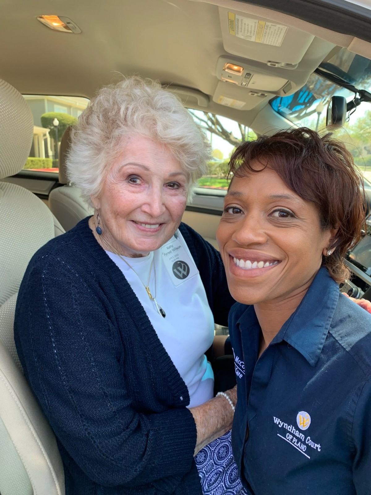 An elderly woman and a young woman smiling for a selfie inside a car.